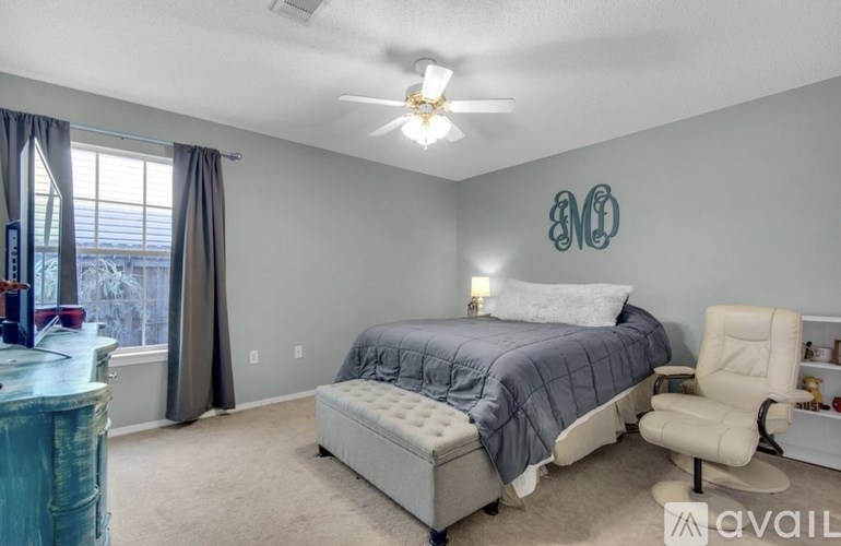 A bedroom with a bed, chair, and a ceiling fan.