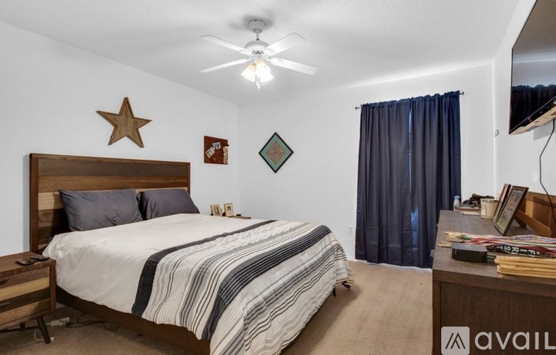 A bedroom with a bed, nightstand, and a ceiling fan.