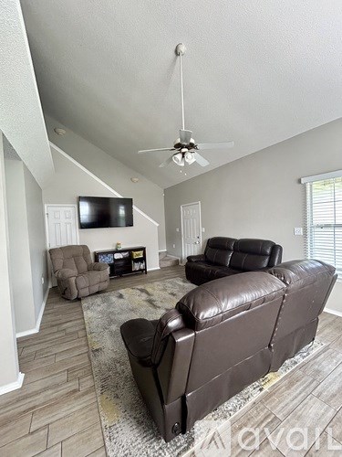 A living room with a brown leather couch and a flat screen TV mounted on the wall.