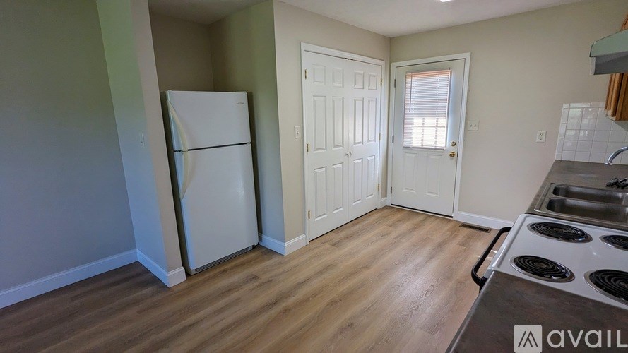 A kitchen with a white fridge and wooden floors.