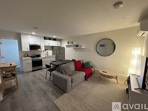 A living room with a grey couch and a round mirror on the wall.