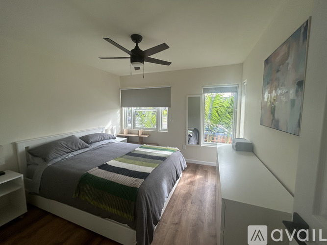 A bedroom with a bed, a ceiling fan, and a window with a view of greenery outside.