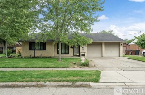 A house with a front yard and a tree in front of it.