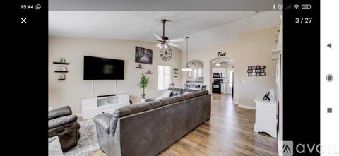 A living room with a brown leather couch and a flat screen TV mounted on the wall.