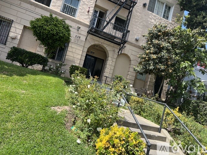 A building with a balcony and a tree in front of it.