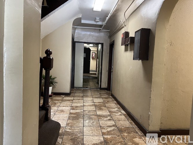 A long hallway with a plant on the left and a door at the end.