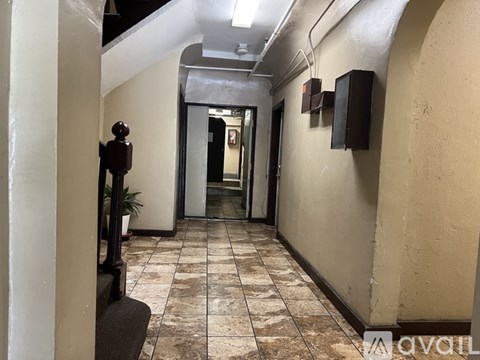 A long hallway with a plant on the left and a door at the end.