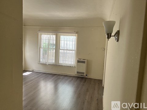 A room with a window and a lamp on the wall.