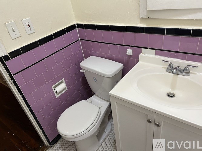 A white toilet and sink in a bathroom with purple tiles.