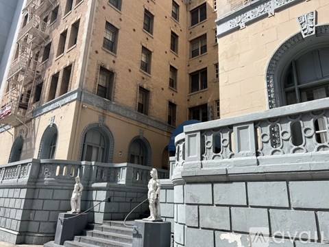 A building with a grey railing and two statues on the steps.