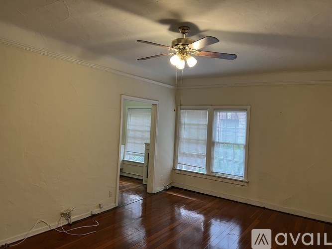 A room with a ceiling fan and two windows.