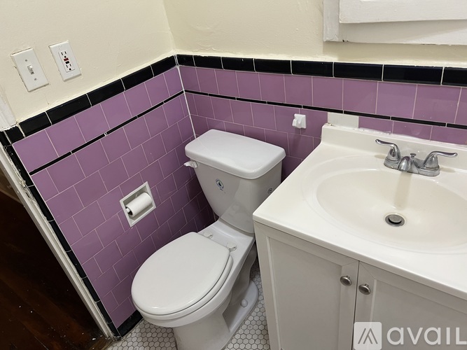 A white toilet and sink in a bathroom with purple tiles.