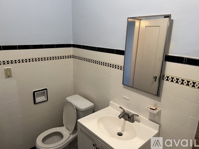 A bathroom with a toilet, sink and mirror.