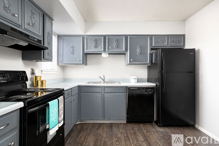 A kitchen with black appliances and grey cabinets.