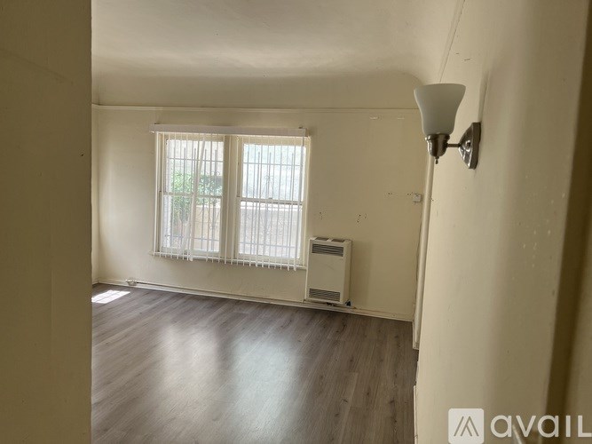 A room with a window and a lamp on the wall.