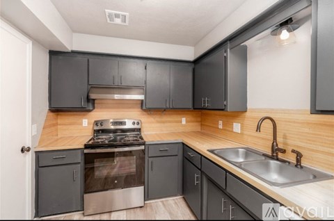 A kitchen with a stove, sink, and cabinets.