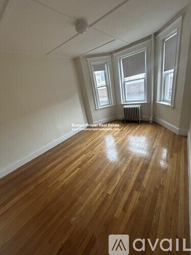 A room with wooden floors and three windows.