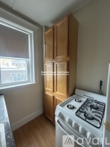 A small kitchen with a white stove and wooden cabinets.