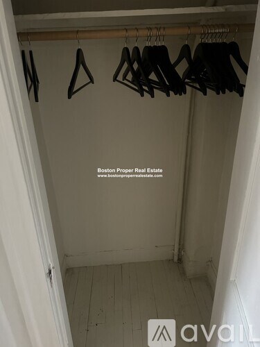 A white closet with clothes hanging on hangers.