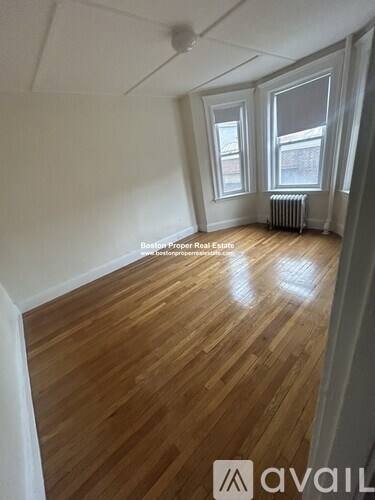 A room with wooden floors and two windows.