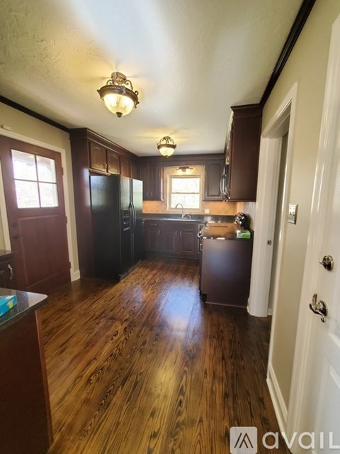 A kitchen with dark wood floors and a black refrigerator.