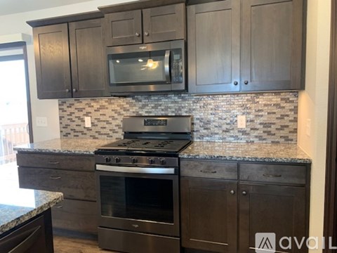A kitchen with dark brown cabinets and a granite countertop.