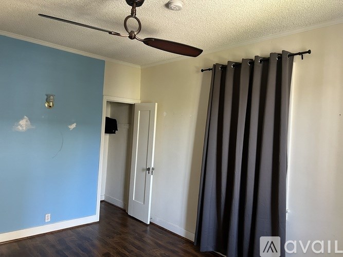 A room with a ceiling fan and a blue wall.
