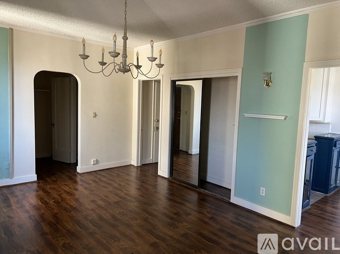 A room with a chandelier and hardwood floors.