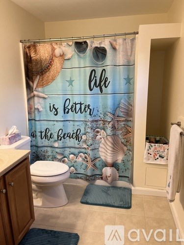 A bathroom with a shower curtain that says "life is better at the beach".