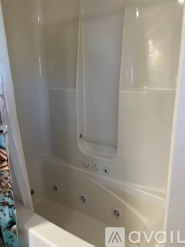 A white bathtub with a shower door and a shower head.