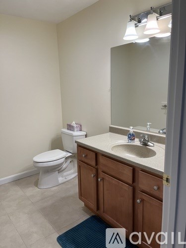 A bathroom with a toilet, sink, and mirror.