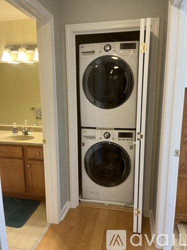 A white front loading washing machine is in a cabinet in a kitchen.