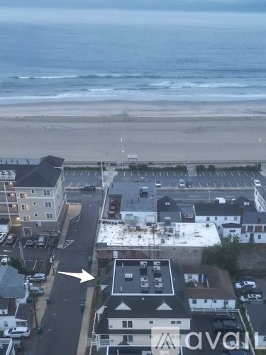 A beachfront view with a parking lot and buildings.