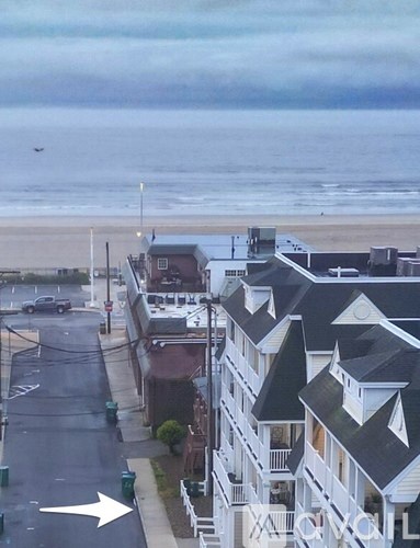 A street view of a residential area with a white arrow pointing to the left.