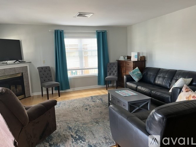 A living room with a black leather couch, a brown chair, and a television.