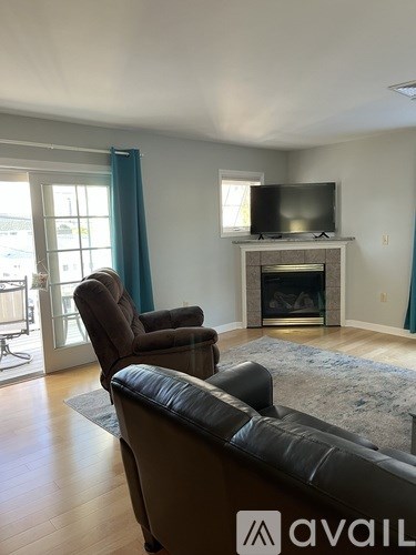 A living room with a leather couch, a chair, and a television.