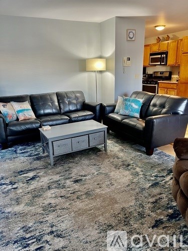 A living room with two black leather sofas and a grey coffee table.