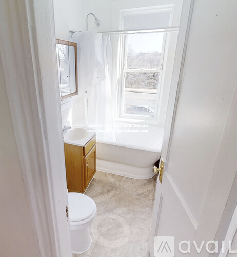 A white bathroom with a toilet, sink, and window.