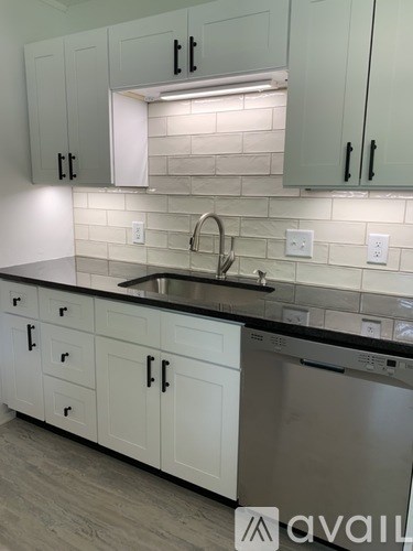 A kitchen with white cabinets and a stainless steel dishwasher.