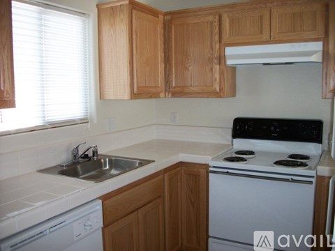 A kitchen with wooden cabinets and a white stove top oven.