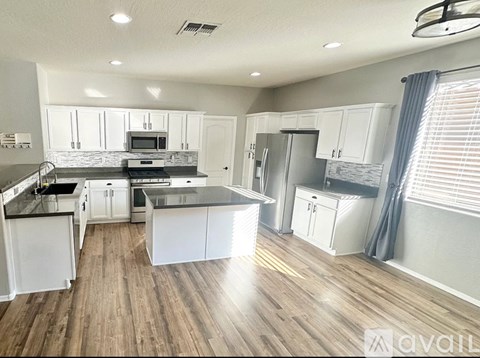 A spacious kitchen with white cabinets and a wooden floor.