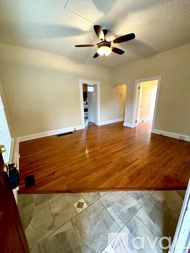 A room with a ceiling fan and wooden floors.