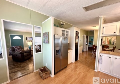 A kitchen with a refrigerator, a dining table with chairs, and a living room with a couch and a chair.