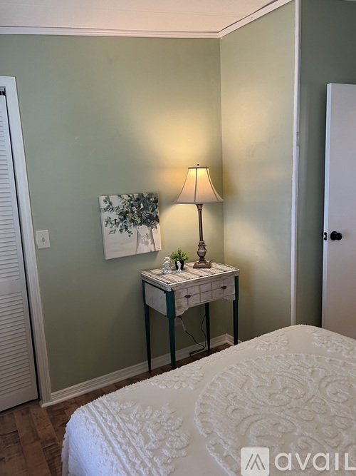 A bedroom with a bed, a nightstand with a lamp, and a painting on the wall.