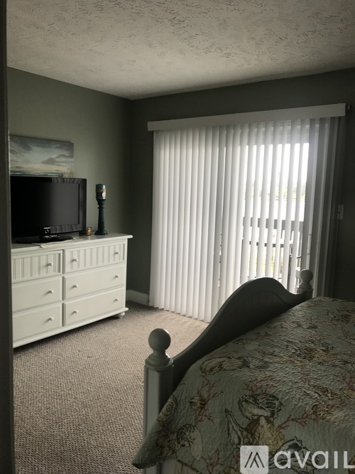 A bedroom with a bed, dresser, and television.