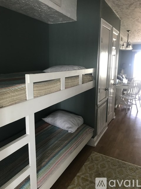 A room with two bunk beds and a dining area.