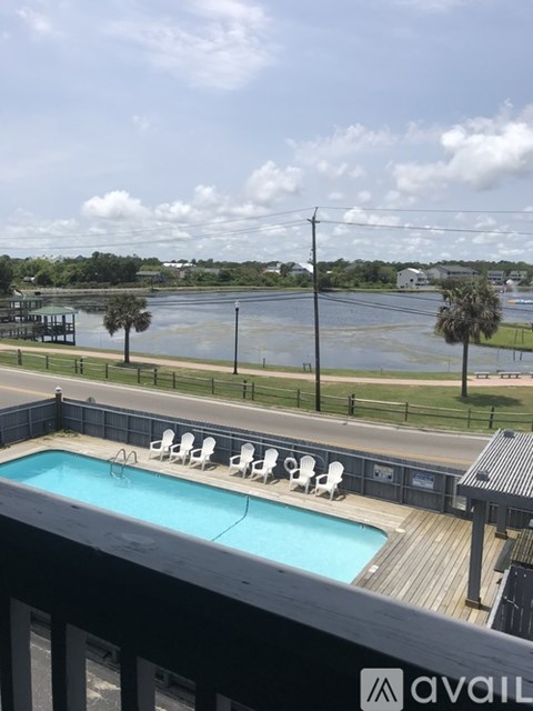 A pool with chairs and a view of a body of water.