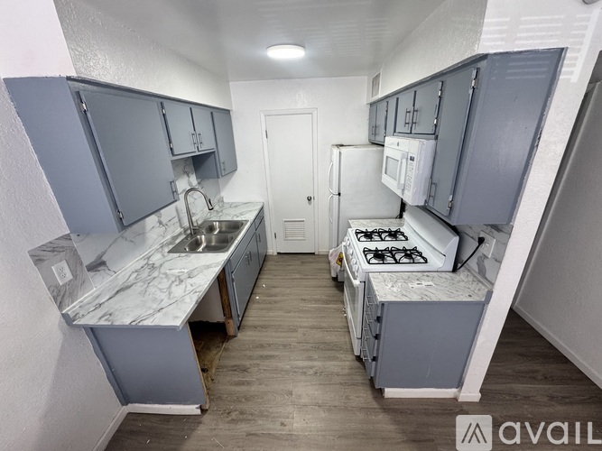 A kitchen with a stove, sink, and cabinets.