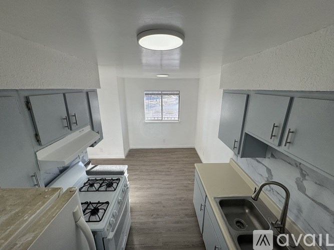 A kitchen with a stove, sink, and cabinets.