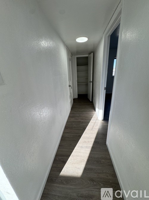 A long hallway with white walls and a light on the ceiling.